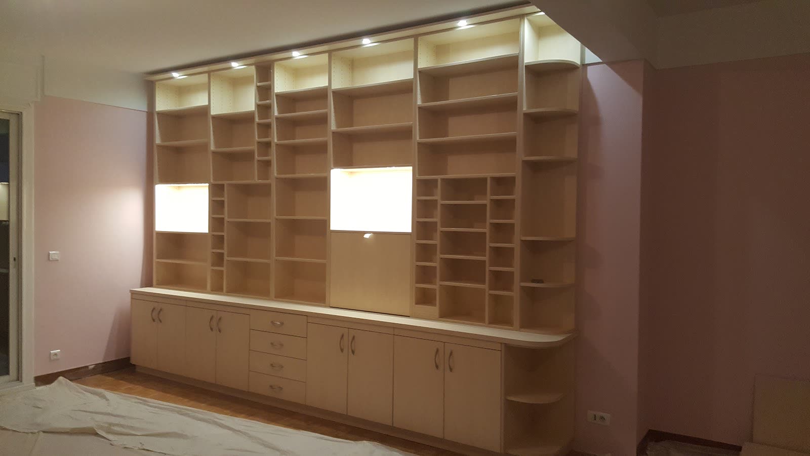 Aménagement mural en bois avec niches, placards et tiroirs conçu pour une grande pièce